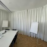Helles Meetingraum mit weißen Vorhängen und Flipcharts, ideal für kreative Office Design Lösungen.