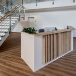 Heller Empfangstresen mit Holzdesign und minimalistischer Einrichtung für modernes Office Design.
