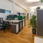 Arbeitsplatz im Büro mit Computer, Pflanzen und moderner Einrichtung.