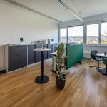 Alt-Text: Modernes Büro mit natürlichen Licht, grüner Pflanzen und flexiblen Arbeitsbereichen.
