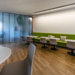Attraktives Office-Design mit modernen Möbeln, grünem Sitzbereich und kreativen Arbeitsbereichen.