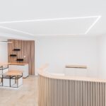 Heller, minimalistischer Empfang mit Holz- und Metallakzenten in einem modernen Bürodesign.