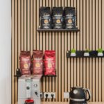 Moderner Kaffeeautomatenbereich in stilvollem Office-Design mit Pflanzen und Kaffeeaccessoires.