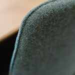 Close-up of green, textured fabric along a curved seam, showing woven pattern and tiny fibers.