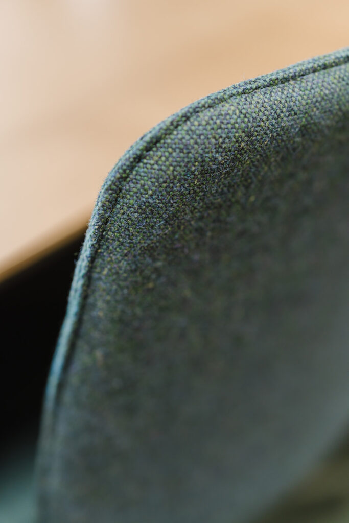 Close-up of green, textured fabric along a curved seam, showing woven pattern and tiny fibers.