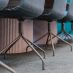 Close-up of blue upholstered conference chairs with metal sled bases under a wooden table.